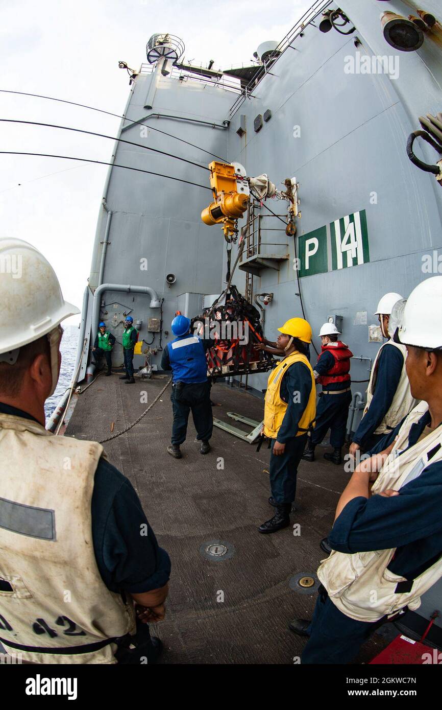 U.S. Navy sailors aboard USS Germantown (LSD 42) remove the lubricant oil cans from the USNS Tippecanoe during a replenishment-at-sea (RAS) in the Pacific Ocean, July 8, 2021. A RAS allows vessels to obtain essential goods without pulling into port so that they can continue operations within their assigned areas. The 31st Marine Expeditionary Unit is operating aboard ships of the America Expeditionary Ready Group in the U.S. 7th fleet area of operations to enhance interoperability with allies and partners and serve as a ready response force to defend peace and stability in the Indo-Pacific reg Stock Photo