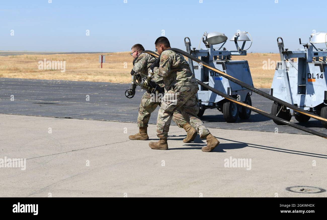 Airman 1st Class Corbin Ney, left, and Staff Sgt. Peter John Mandadero, right, 9th Logistics Readiness Squadron Immediate Response Force team members, carry fuel hoses down the flightline during an exercise July 9, 2021, at Beale Air Force Base, California. This exercise served to test the new expeditionary refueling system at Beale. Stock Photo