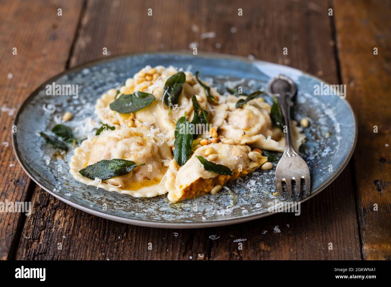 Home made pumpkin ravioli with crispy sage leaves and pinenuts Stock Photo