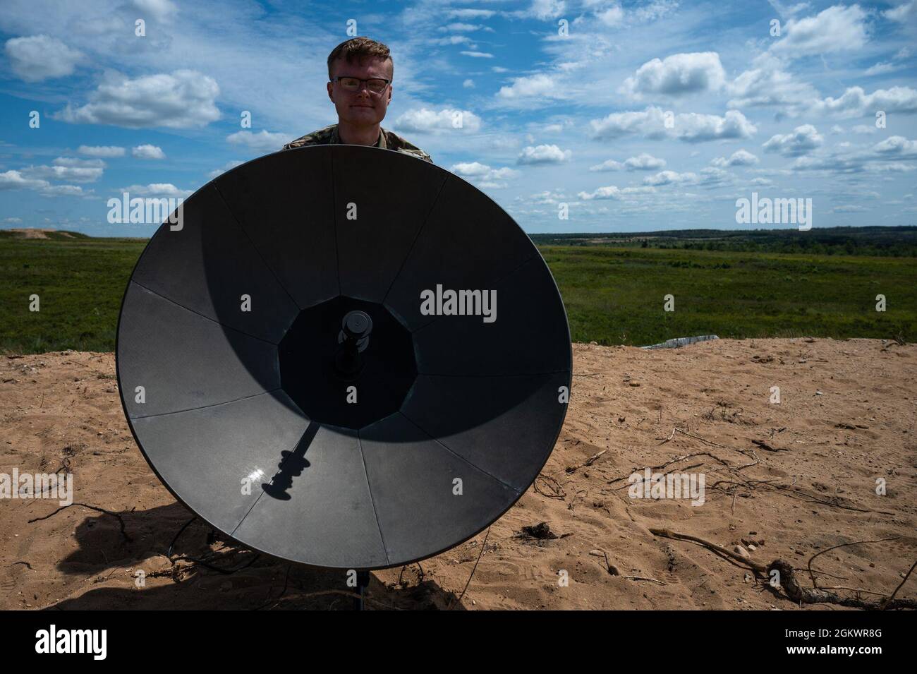 U.S. Air Force Staff Sgt. Thomas Hill, 1st Combat Camera Squadron Cyber Systems technician, alines a Tampa Microwave Satellite Terminal to receive signal while supporting a combat camera team during the Global Information Dominance Experiment 3 and Architect Demonstration Evaluation 5 at Camp Grayling, Michigan, July, 12, 2021. The North American Aerospace Defense Command and U.S. Northern Command, NORAD and USNORTHCOM, in partnership with all 11 Combatant Commands, led the third in a series of Global Information Dominance Experiments designed to rapidly develop the capabilities required to in Stock Photo