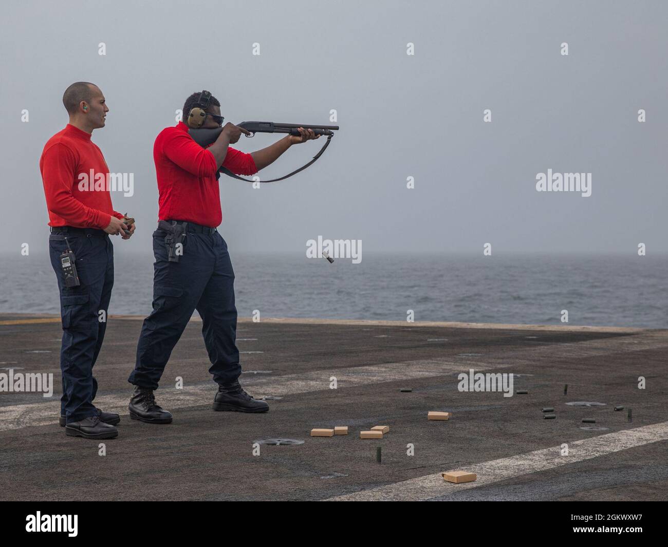 210713-N-NY362-1046 GULF OF ADEN (July 13, 2020) – Master-at-Arms 1st Class Belisario Salas, left, observes Master-at-Arms 3rd Class Lenny Lee as he fires an M500 shotgun during a live-fire exercise aboard aircraft carrier USS Ronald Reagan (CVN 76) in the Gulf of Aden, July 13. Ronald Reagan is deployed to the U.S. 5th Fleet area of operations in support of naval operations to ensure maritime stability and security in the Central Region, connecting the Mediterranean and the Pacific through the western Indian Ocean and three strategic choke points. Stock Photo