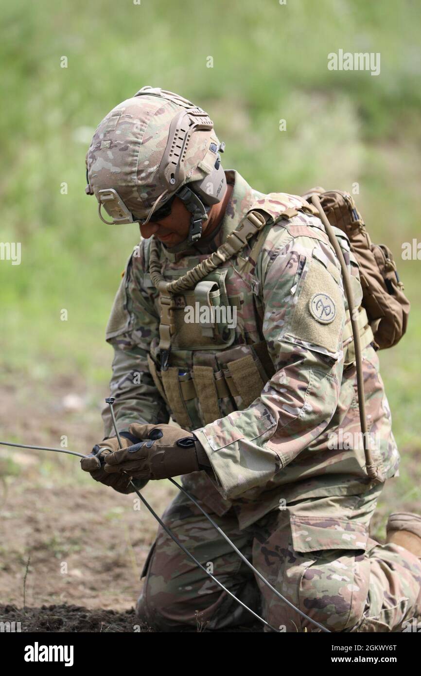 Staff Sgt. Manuel Olivo, a combat engineer assigned to the New York Army National Guard's Bravo Company, 152nd Brigade Engineer Battalion, ties a C4 explosive charge into a line of detonation cord during demolition training at Fort Drum, New York on July 13, 2021. As part of the company's annual training, combat and horizontal construction engineers practiced emplacing C4 explosives, shaping and cratering charges, bangalore torpedoes, and explosively formed projectiles. Stock Photo