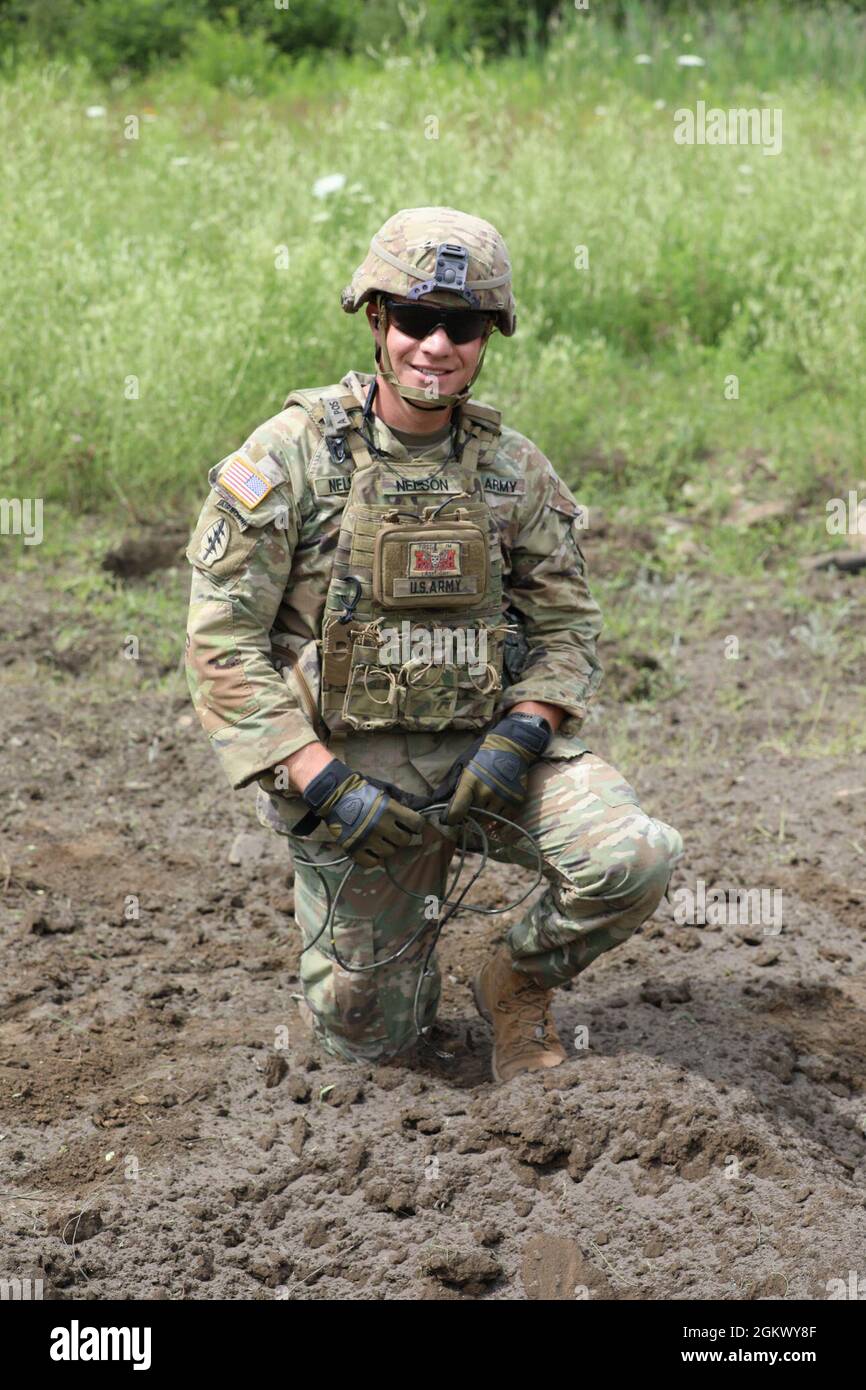 New York Army National Guard Sgt. Dakota Nelson, a horizontal construction engineer assigned to Bravo Company, 152nd Brigade Engineer Battalion, poses on the ground where he set off a C4 explosive charge during demolition training at Fort Drum, New York on July 13, 2021. As part of the company's annual training, combat and horizontal construction engineers practiced emplacing C4 explosives, shaping and cratering charges, bangalore torpedoes, and explosively formed projectiles. Stock Photo