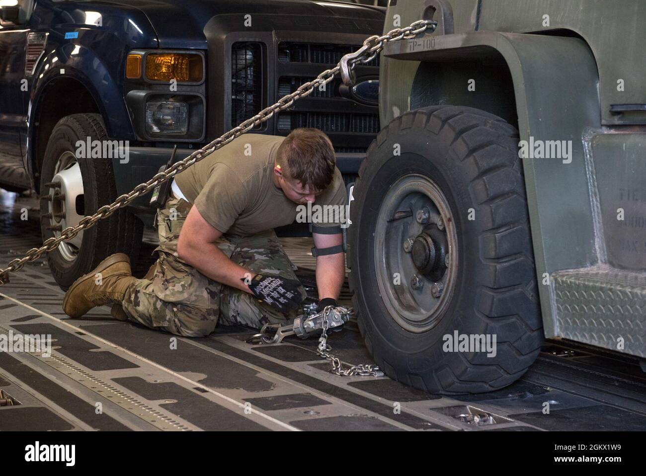 U.S. Air Force Senior Airman Steve Shaffer, an aerial transportation specialist with the 123rd Airlift Wing, Kentucky National Guard, inspects a tie-down chain during a cargo loading exercise at the 167th Airlift Wing, Martinsburg, West Virginia, Jul. 14, 2021. The 167th hosted members from the 123rd for a small air terminal training in preparation for their upcoming deployment. Stock Photo