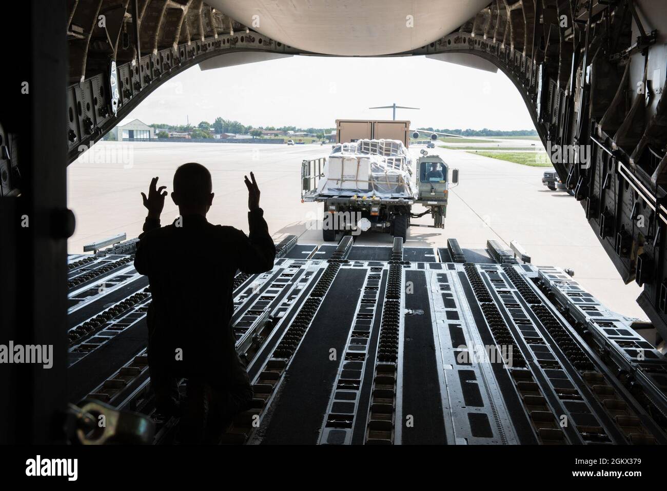 U.S. Air Force Airman 1st Class Sam Bartolomeo, a loadmaster with the 167th Operations Group, directs Staff Sgt. James Ford, an aerial transportation specialist with the 123rd Airlift Wing, Kentucky National Guard, while palletized cargo is loaded onto a C-17 Globemaster III aircraft using a container loader during a cargo loading exercise at the 167th Airlift Wing, Martinsburg, West Virginia, Jul. 14, 2021. The 167th hosted members from the 123rd for a small air terminal training in preparation for their upcoming deployment. Stock Photo
