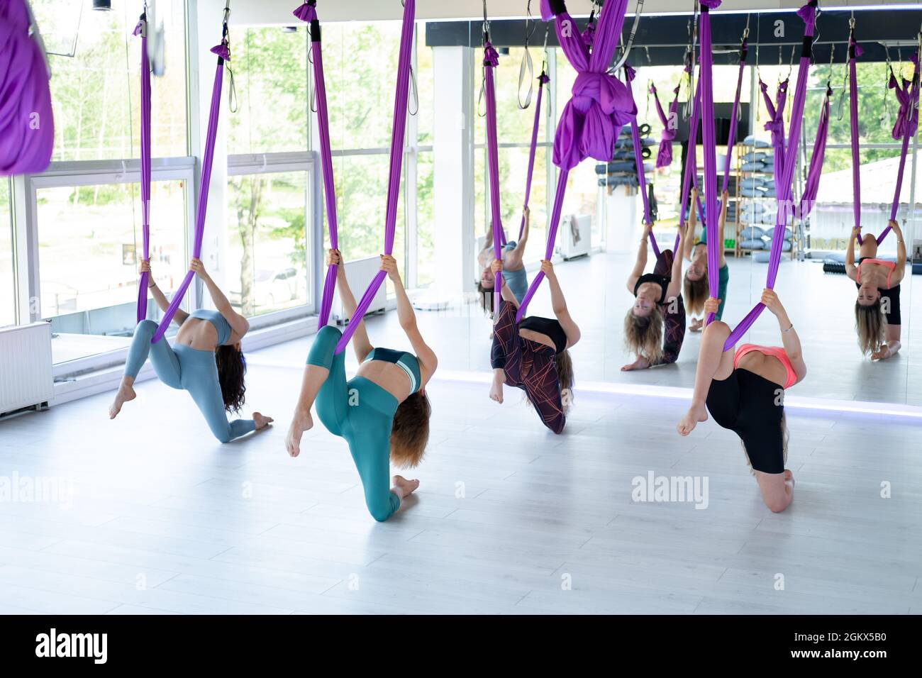 Group of young women practice in aero stretching swing. Aerial flying yoga exercises practice in purple hammock in fitness club Stock Photo Alamy