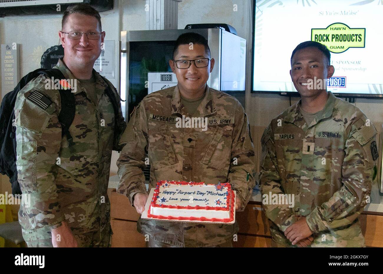 Spc. Michael McGeary, a satellite communication systems operator (MOS-25S) with the 11th Signal Brigade, center, celebrates the anniversary of his adoption with a cake sent from his parents, with his platoon sergeant and platoon leader, Staff Sgt. Brian Seymour, a nodal network systems operator, left, and 1st Lt. Ruben Yapias, a signal officer, right, during Forager 21, at Andersen Air Force Base, Guam, July 16, 2021. McGeary grew up in Michigan and was adopted by his parents from South Korea. Stock Photo