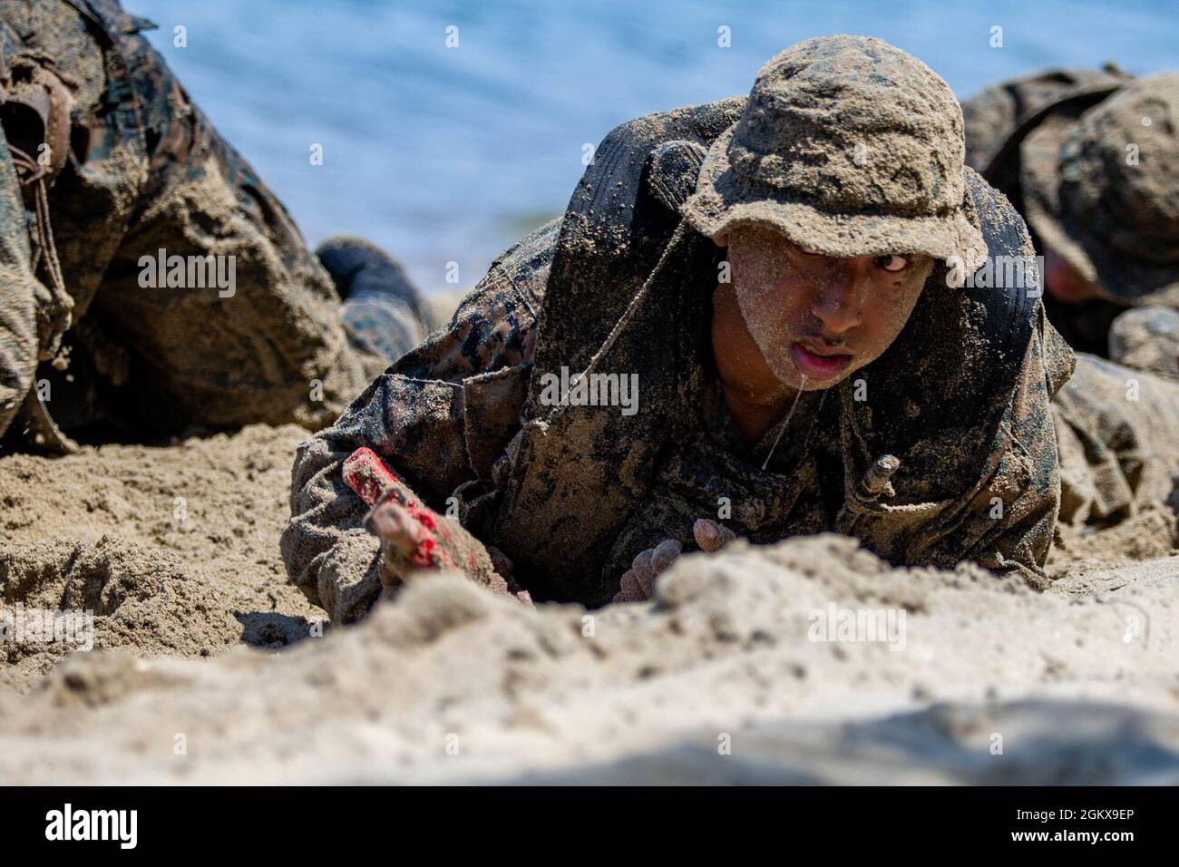 U.S. Marine Corps Lance Cpl. Isaiah Ellinger, a rifleman with Co. C, 1st Battalion, 5th Marine Regiment, 1st Marine Division, low crawls on the beach during a Scout Swimmer Course on Naval Amphibious Base Coronado, California, July 16, 2021. The Marines learned the skills necessary to plan and execute swimmer reconnaissance for a small boat raid company in preparation for deployment. Stock Photo