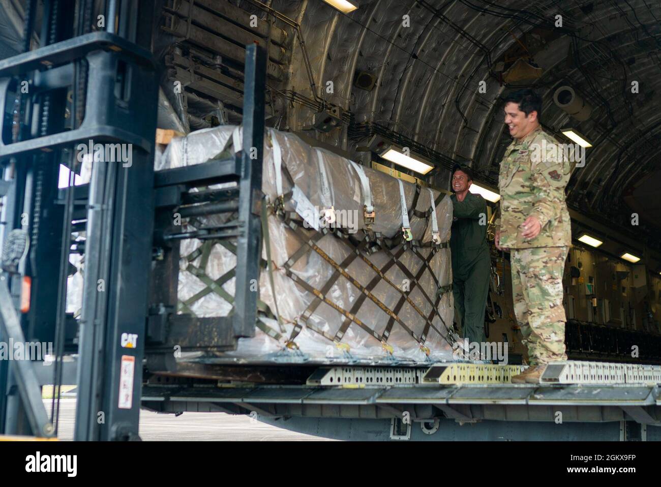 U.S. Air Force Maj. Noah Davis, C-17 Globemaster III aircraft commander, and Staff Sgt. Dwayne Baldwin, loadmaster, both assigned to the 701st Airlift Squadron, push cargo onto a forklift at Johan Adolf Pengel International Airport, Suriname, July 16, 2021. The portable field hospital, valued at $745,000, was donated by U.S. Southern Command Stock Photo