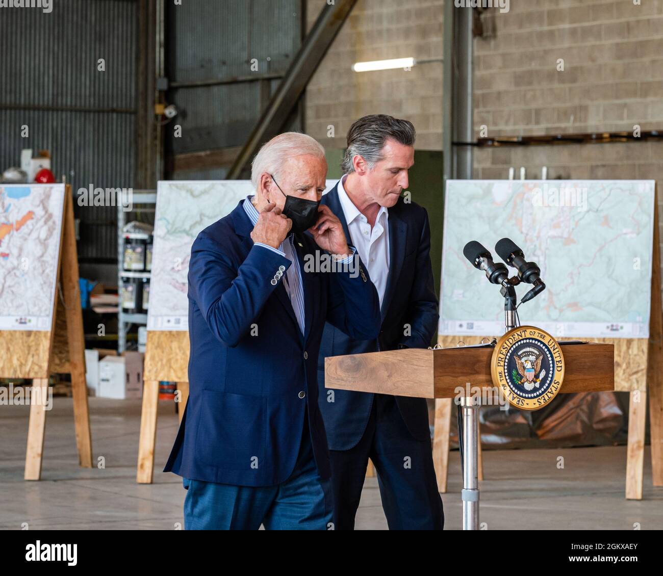 President Biden moves up to a podium at a press conference, removing his mask, after Governor Gavin Newsom has finished speaking. Stock Photo