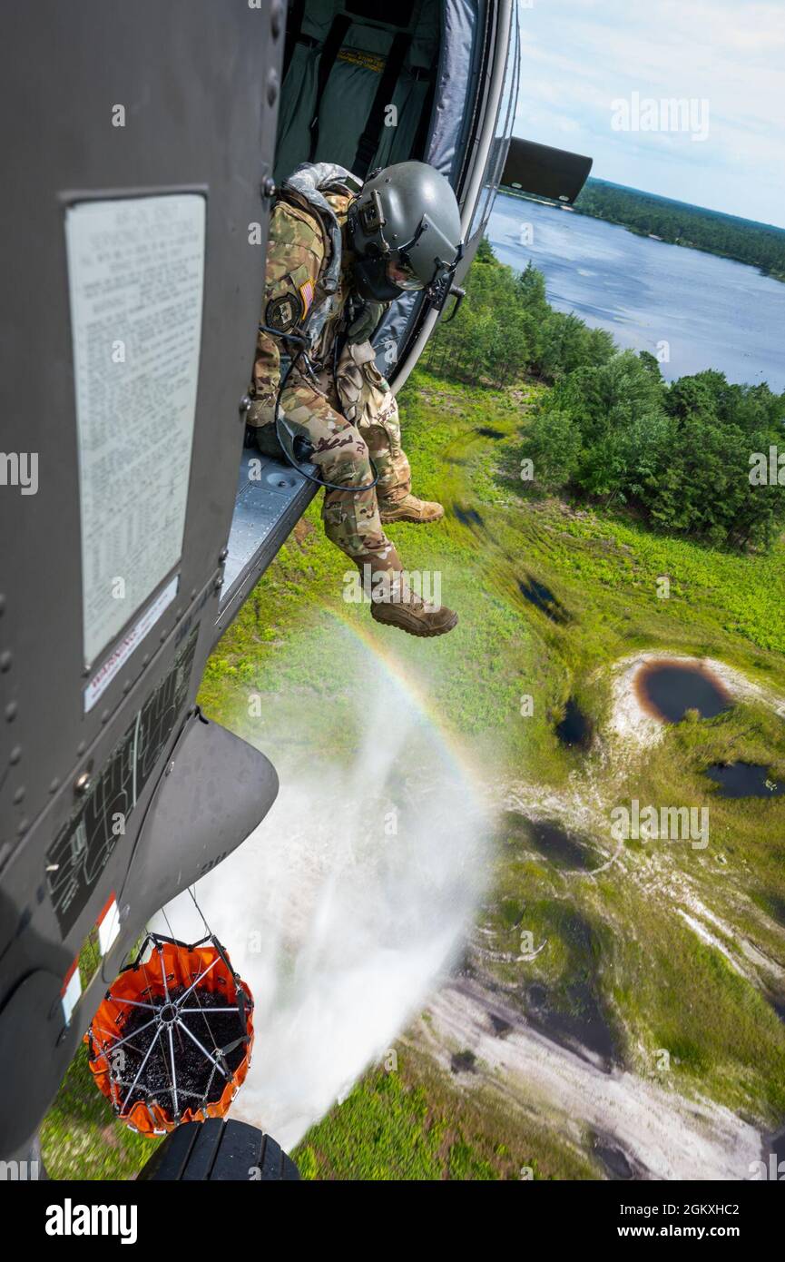 U.S. Army Staff Sgt. Anthony Marotta, a UH-60L Black Hawk helicopter crew chief, sits in a UH-60l Black Hawk during water bucket training at Joint Base McGuire-Dix-Lakehurst, N.J., July 19, 2021. Water bucket training allows National Guard units to assist and protect members of their communities from natural and man-made fire disasters. Stock Photo