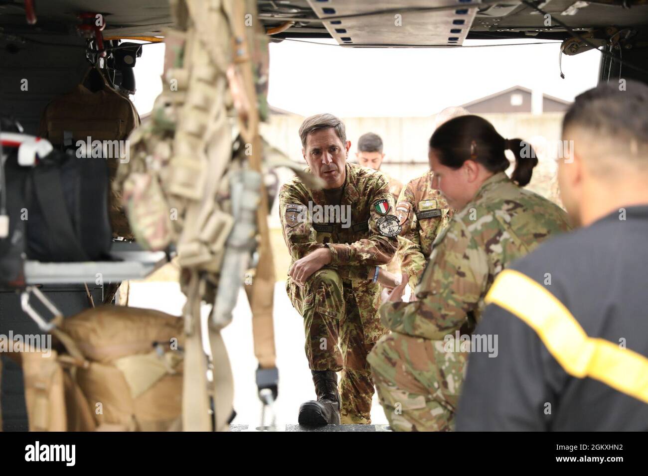 Italian Army Gen. D. Franco Federici, NATO Kosovo Force commander (COMKFOR), looks on as U.S. Army Sgt. Joanna Adams of C Company, 1st Battalion, 169th Aviation Regiment, gives instruction on patient loading procedures for Medevac missions at Camp Bondsteel, Kosovo July 16, 2021. COMKFOR and his staff were visiting with various NATO partners to see how they perform their missions. This image was electronically cropped and ethically enhanced to emphasize the subject and does not misrepresent the subject or the original image in any way. Stock Photo