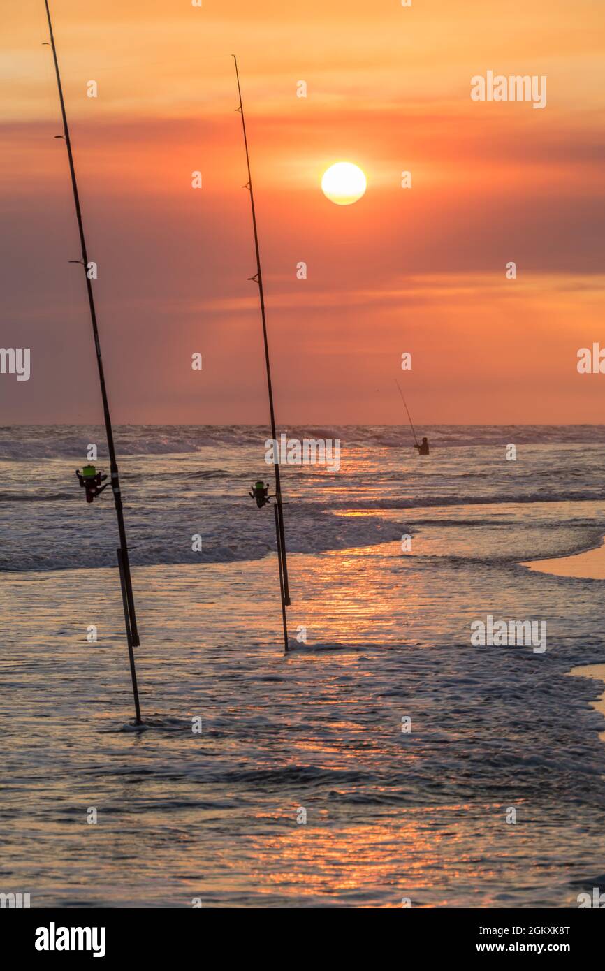 Fishing rod with fishing reel on the beach on a beautiful sunset