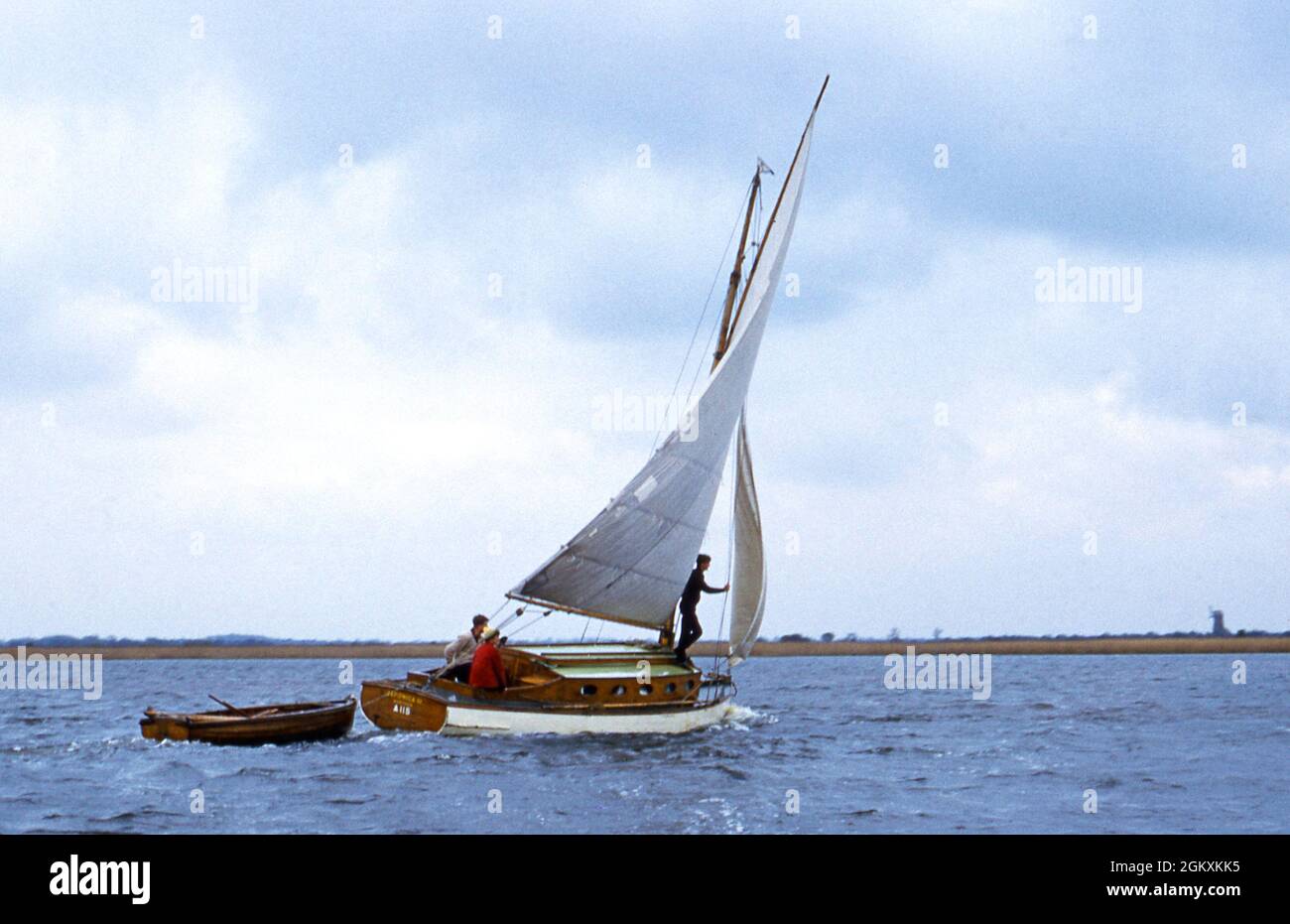 Sailing a yacht towing a dinghy on Horsey Mere, Norfolk, England Stock