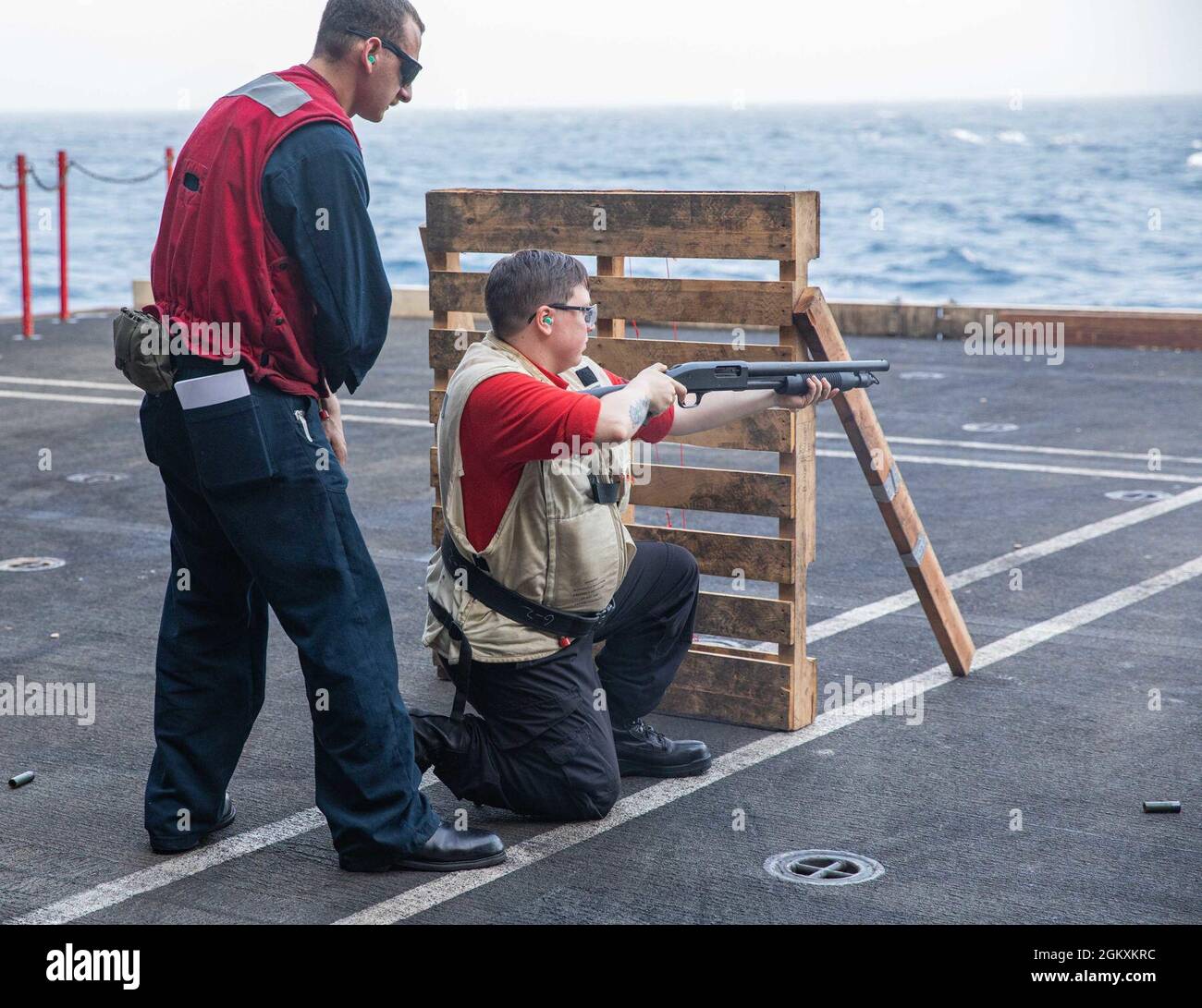 210720-N-NY362-1067 ARABIAN SEA (July 20, 2021) – Master-at-Arms 2nd Class Amanda Wagner, right, fires an M500 shotgun during a live-fire qualification course aboard aircraft carrier USS Ronald Reagan (CVN 76) in the Arabian Sea, July 20. Ronald Reagan is deployed to the U.S. 5th Fleet area of operations in support of naval operations to ensure maritime stability and security in the Central Region, connecting the Mediterranean and Pacific through the western Indian Ocean and three strategic choke points. Stock Photo