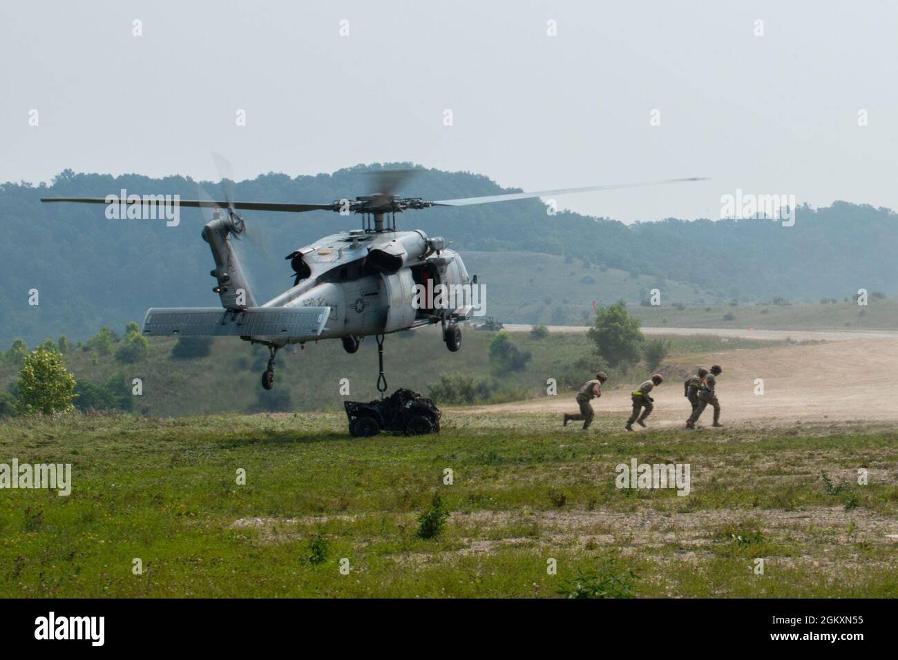 Soldiers from the 123rd Airlift Wing, Kentucky Air National Guard and a Navy MH-60 Seahawk from Helicopter Sea Combat Squadron Nine, Naval Air Station Norfolk, Virginia, offload an all-terrain vehicle during sling load training, during Sentry Storm 2021 at Camp Branch, Logan County, West Virginia, July 20, 2021. Stock Photo