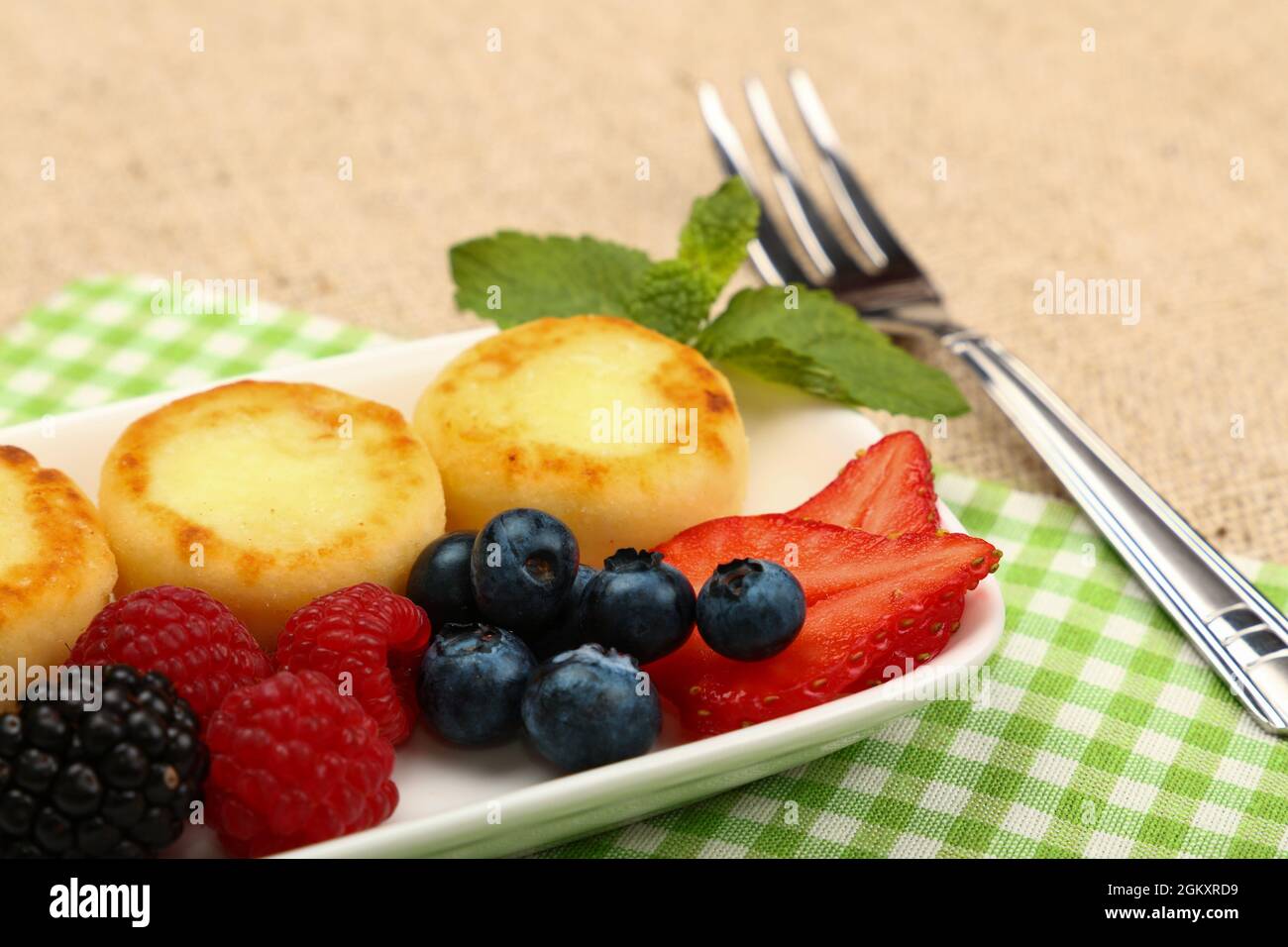 Close up serving portion of European quark cheese pancakes dessert with fruits on table, high angle view, personal perspective Stock Photo