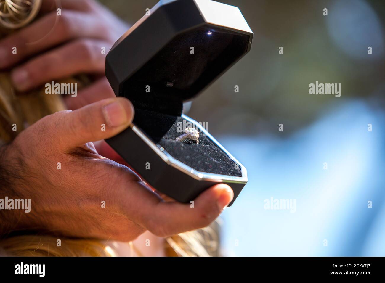 Wedding ring with diamonds in black elegant box. Man holds an open jewellery box with expensive proposal ring Stock Photo