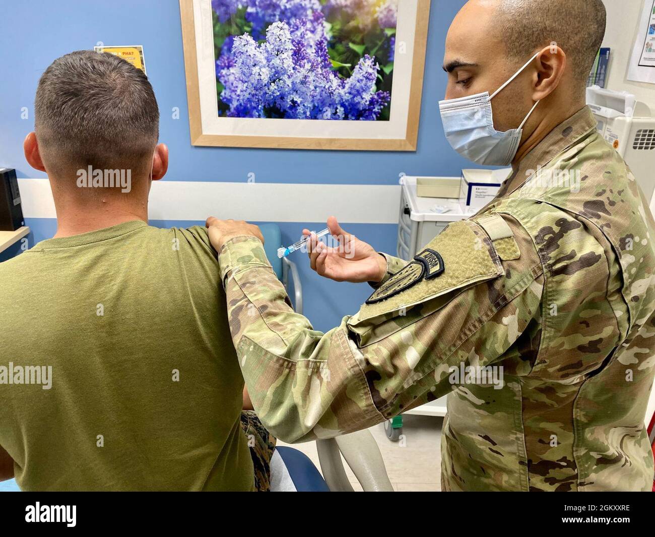 Sgt. Jonathan Harris, 3rd Battalion, 353rd Infantry Regiment, vaccinates Lance Cpl. Mason Brennan, 1st Battalion, 23rd Marine Regiment at the Soldier Center Medical Home clinic during his annual periodic health assessment at the Joint Readiness Training Center and Fort Polk, La. on July 22. Stock Photo