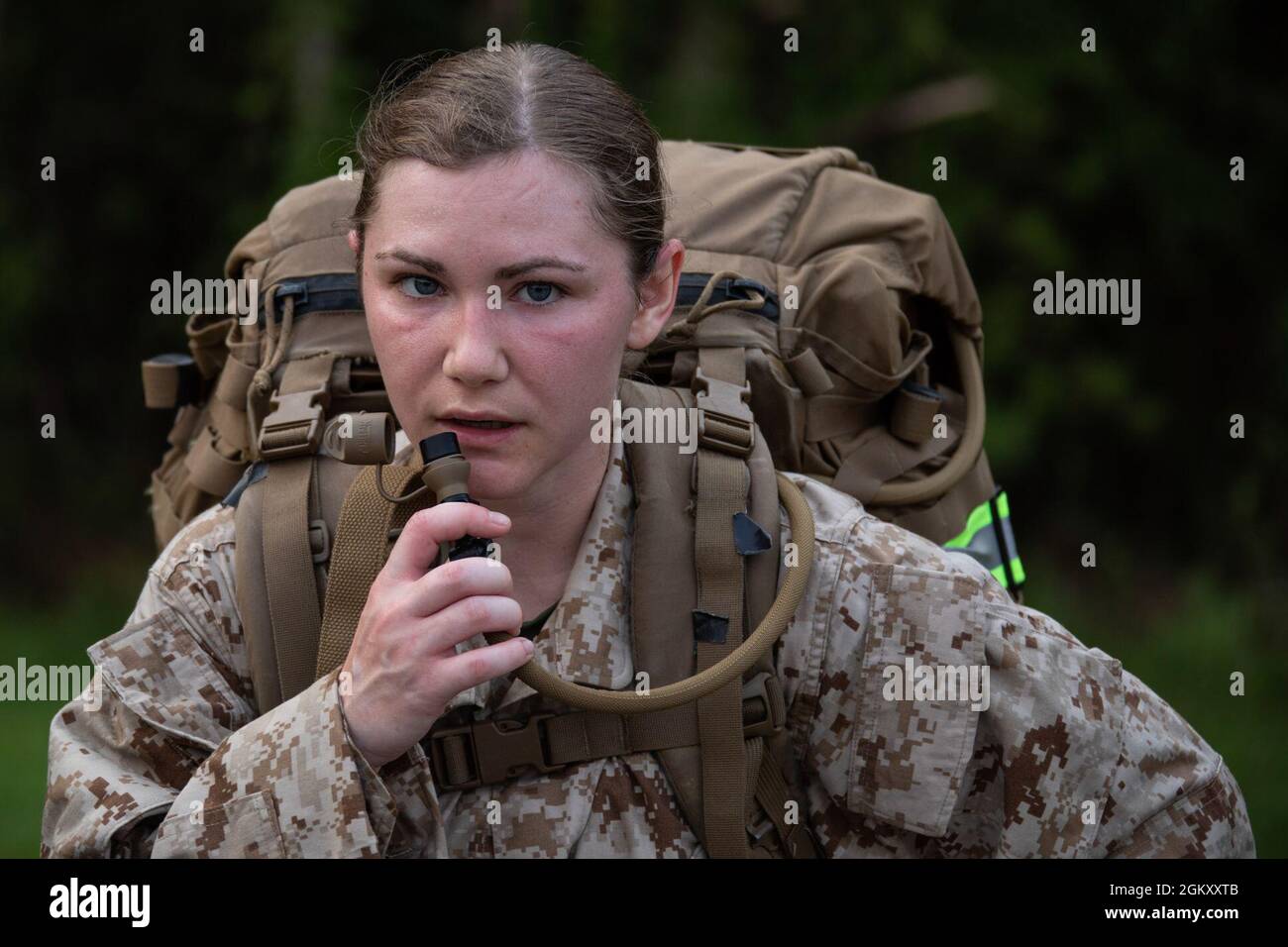 U.S. Navy Hospitalman Morgan D. Miki, a student with Field Medical Training Battalion-East (FMTB-E), Training Command, hydrates at a stopping point during a two-mile hike on Camp Johnson, N.C., July 22, 2021. Students of FMTB-E participate in four different hikes during a normal training evolution to better prepare themselves for the physical rigors of being attached to their future U.S. Marine Corps units. Stock Photo