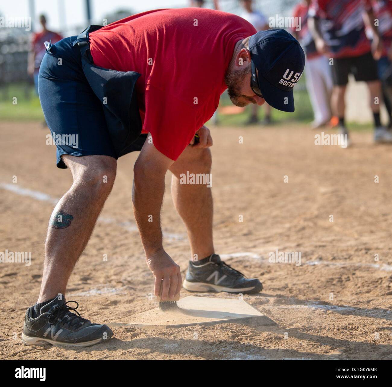 David Patch, volunteer umpire, cleans off home plate during an intramural softball game between the 436th Security Forces Squadron and the 436th Maintenance Squadron Isochronal Maintenance Dock on Dover Air Force Base, Delaware, July 26, 2021. The 436th SFS won the game 13-4. Stock Photo