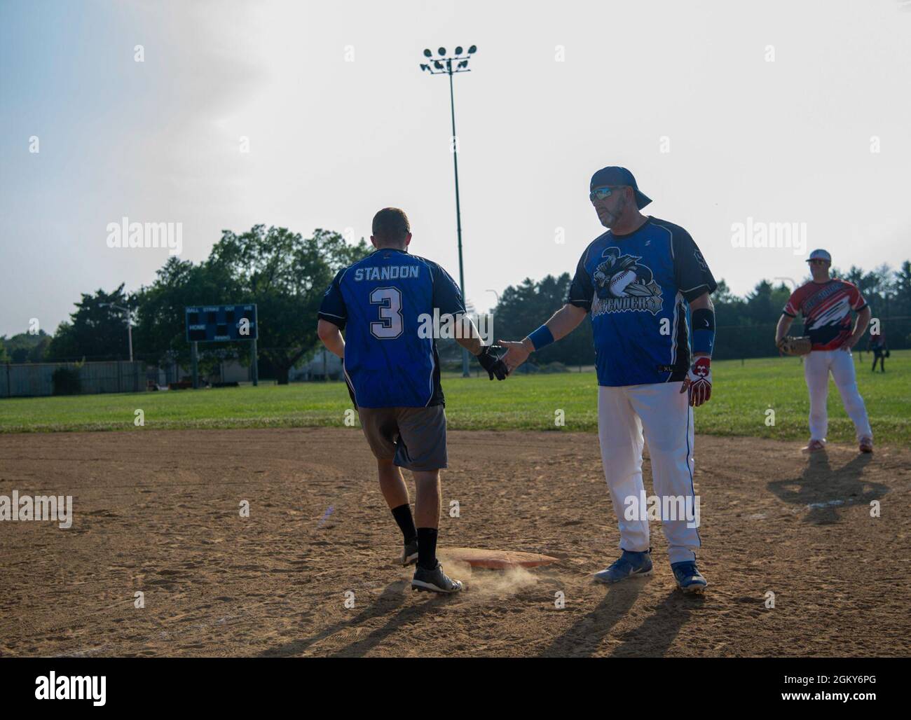 Richard Barker, right, 436th Security Forces Squadron security specialist, high fives Senior Airman Nicholas Standon, 436th SFS response force member, after reaching first base during an intramural softball game against the 436th Maintenance Squadron Isochronal Maintenance Dock on Dover Air Force Base, Delaware, July 26, 2021. The 436th SFS won the game 13-4. Stock Photo