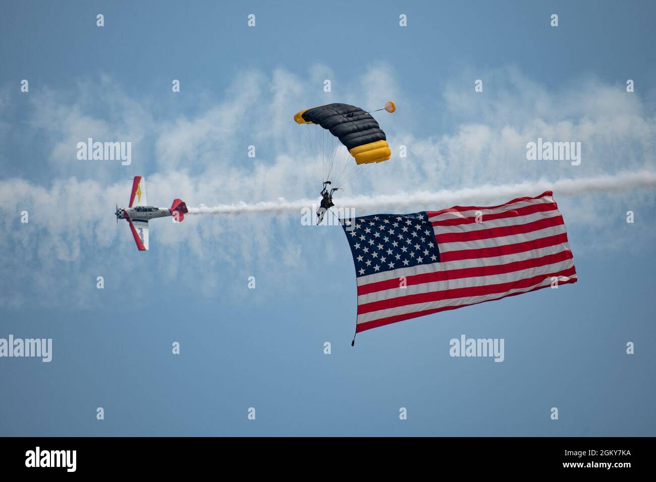 A U.S. Special Operations Command Parachute Team Para-Commando and an Aeroshell Acrobatic Team AT-6 Texan aircraft perform during EAA AirVenture Oshkosh 21, at Oshkosh, Wis., July 26, 2021. The airshow featured various civilian and military aircraft, to include the Warbirds of America, Aeroshell, SOCOM and Air Force Special Operations Command. The Para-Commandos are comprised of active duty Special Operators, such as Army Special Forces, Army Rangers, Navy SEALs, Air Force Combat Controllers and Marine Raiders. Stock Photo