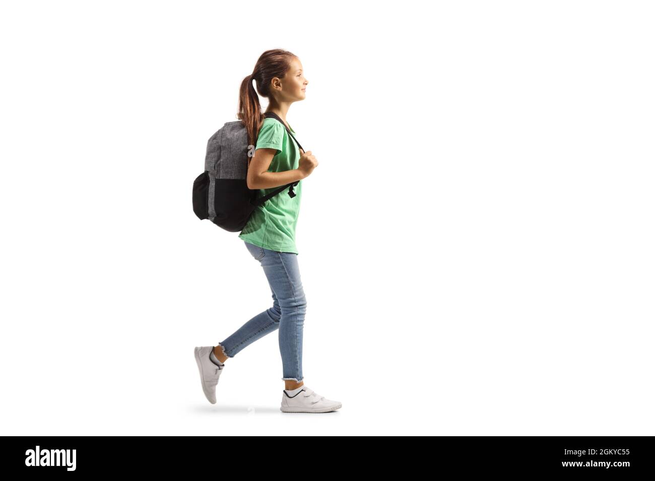 Full length profile shot of a girl carrying a backpack and walking isolated on white background Stock Photo