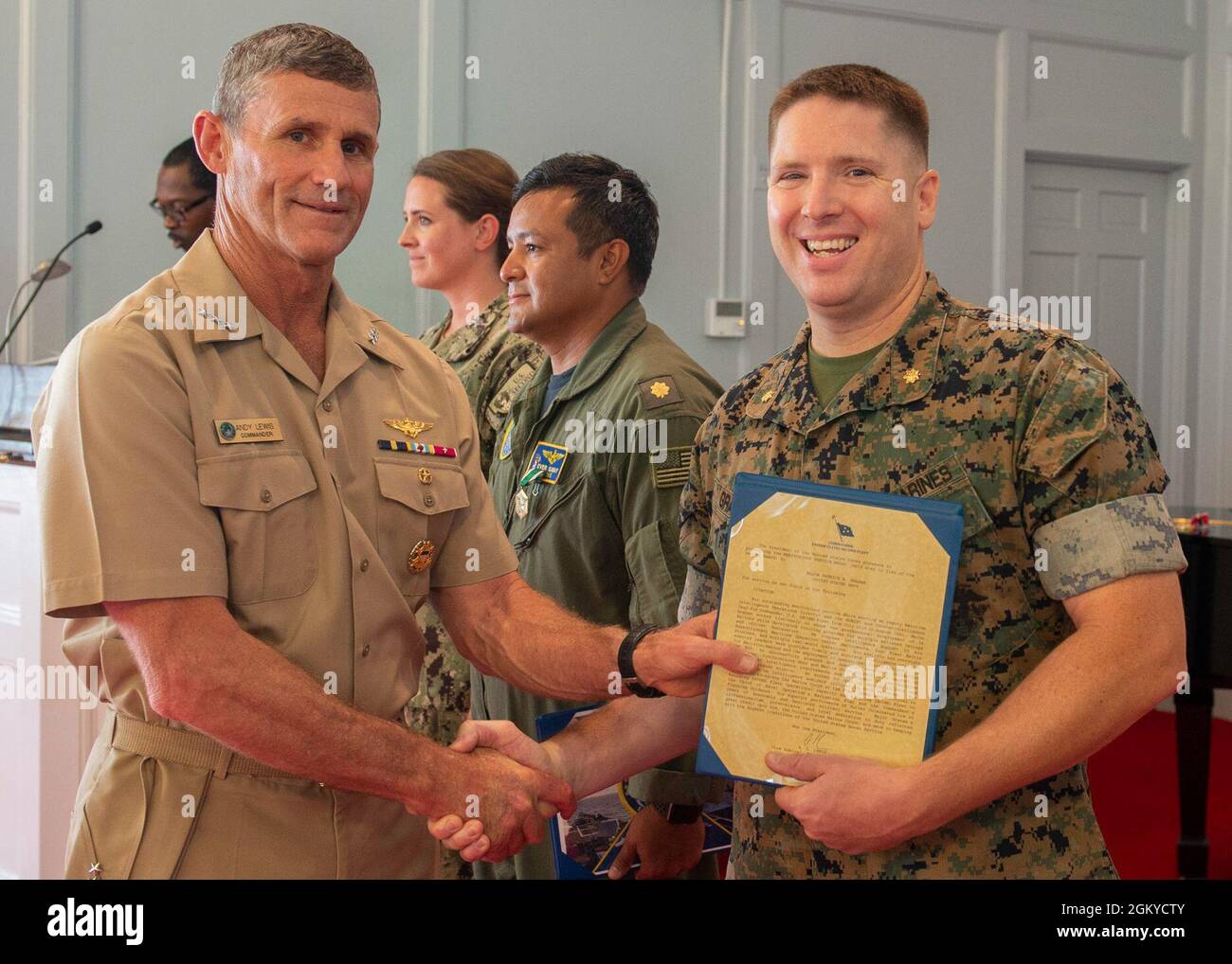 Major Patrick Graham receives a Meritorious Service medal citation from Vice Adm. Andrew Lewis