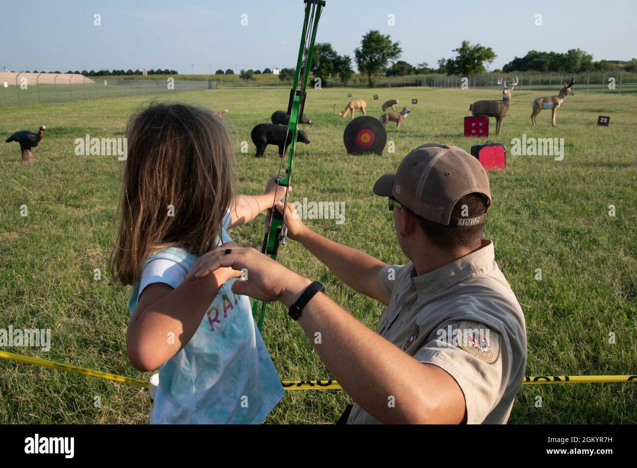 Daniel Perkins, Oklahoma Department of Wildlife Conservation state game  warden helps Genevieve Allen, daughter of U.S. Air Force Master Sgt. Nathan  Allen, 97th Air Mobility Wing public affairs superintendent, shoot her bow