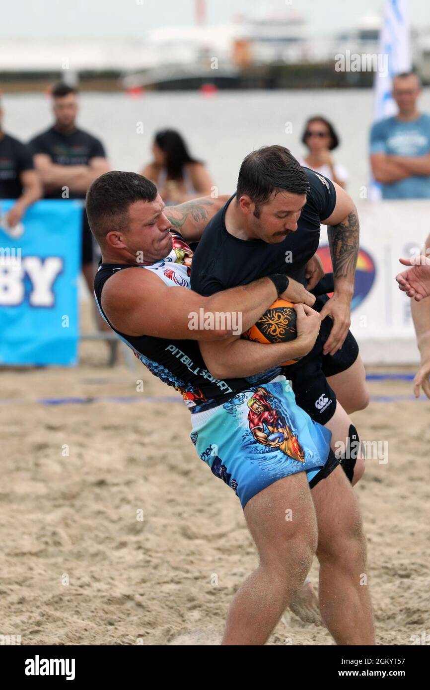 Staff Sgt. Tyler Worthen with B Company, 3rd Battalion “Dark Rifles,” 161st Infantry Regiment, is lifted by a Polish player versus defending champion Posnania in the opening match of the 9th Sopot International Beach Rugby Tournament July 31, 2021 on the main beach in Sopot, Poland. Rugby has an enduring tradition of fellowship through brutal competition. Stock Photo