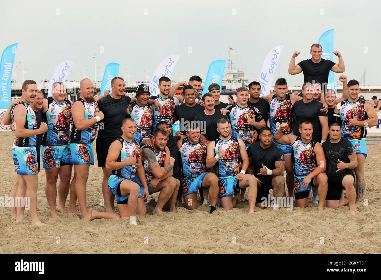 Members of 3rd Battalion “Dark Rifles,” 161st Infantry Regiment (dark jerseys) celebrate with defending champion Posnania after the opening match of the 9th Sopot International Beach Rugby Tournament July 31, 2021 on the main beach in Sopot, Poland. Rugby has an enduring tradition of fellowship through brutal competition with post-match customs emphasizing sportsmanship and camaraderie. Stock Photo