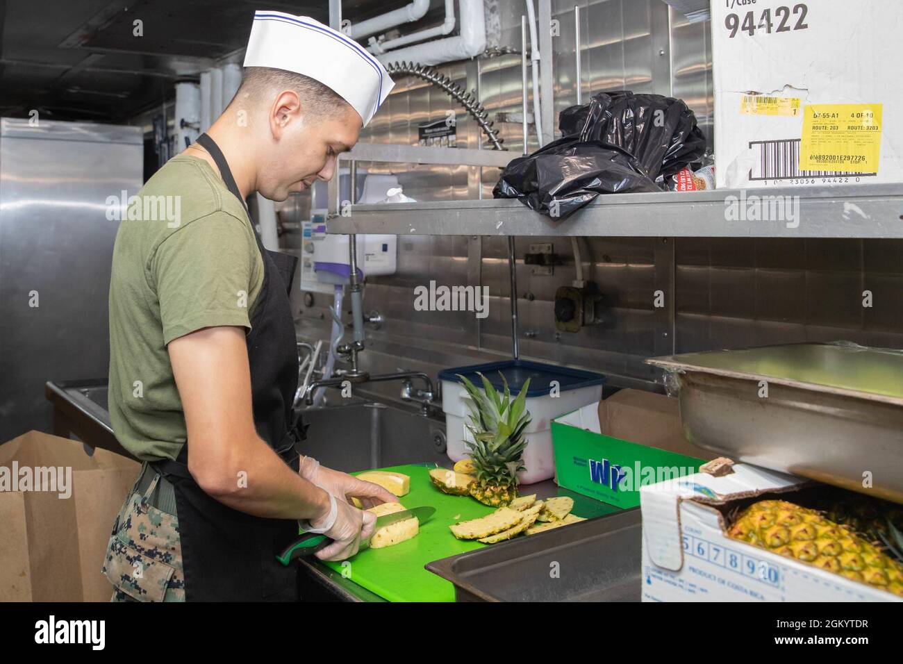 210731-N-JB637-1036 ATLANTIC OCEAN (July 31, 2021) U.S. Marine Corps Cpl. Cristian Puente, a food service specialist assigned to the 22nd Marine Expeditionary Unit, prepares fresh fruit aboard the Wasp-class amphibious assault ship USS Kearsarge (LHD 3) July 31, 2021. Embarked Marines integrate with the ship’s crew to support daily operations while underway. Stock Photo