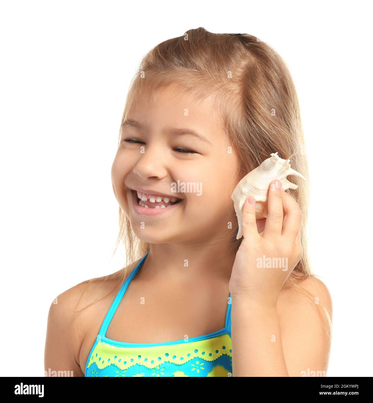 Adorable little girl in swimsuit listening to sea shell on white