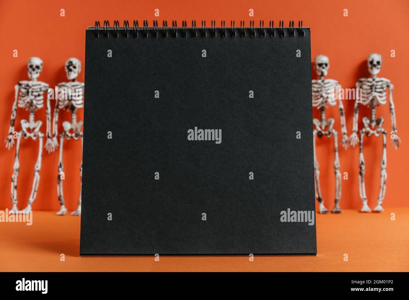 Dead Notebook Background Empty black notebook on an orange background with skeletons in blur ...