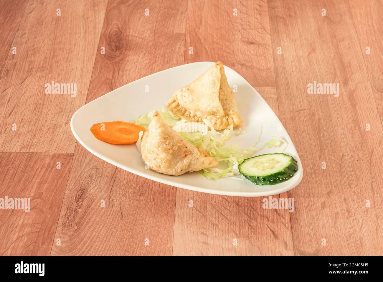 Vegetable samosas cooked in Pakistani kebab restaurant with white plate in Ramadan and wooden table Stock Photo