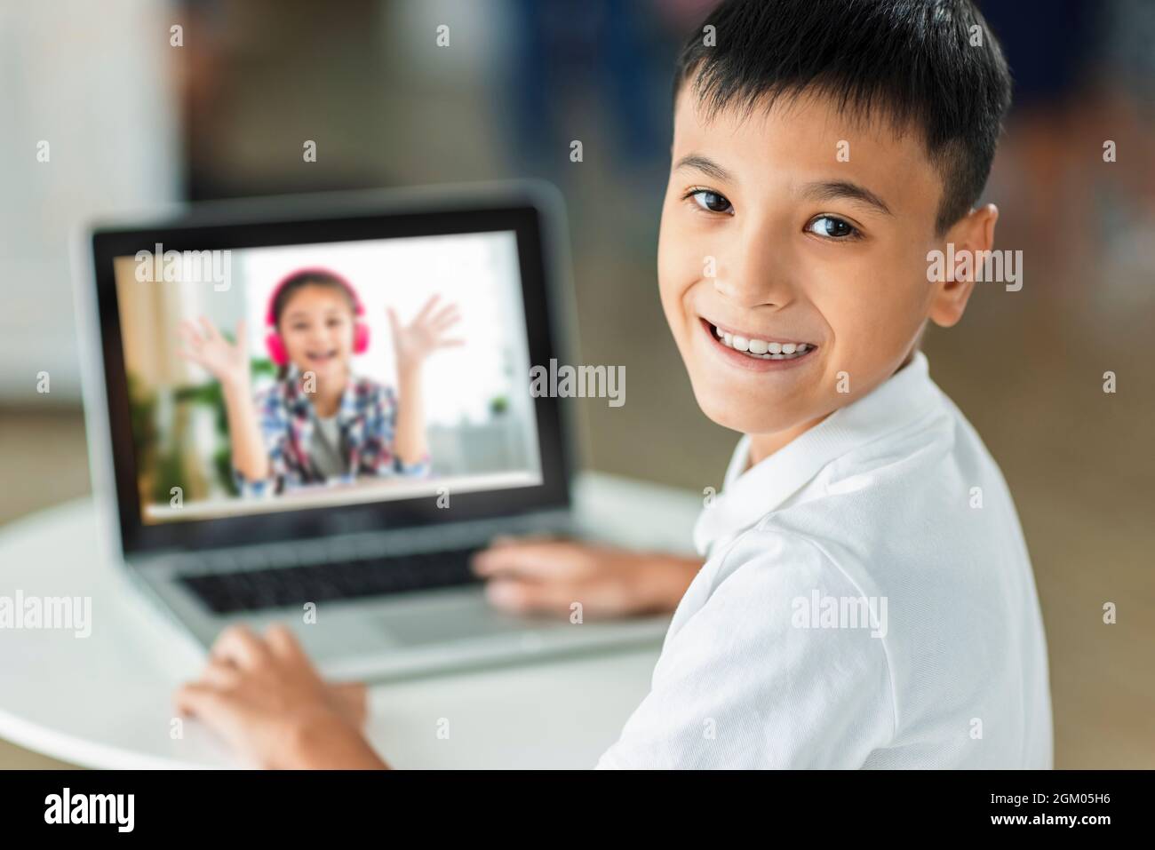 Happy boy meet his classmate online with laptop. Stock Photo