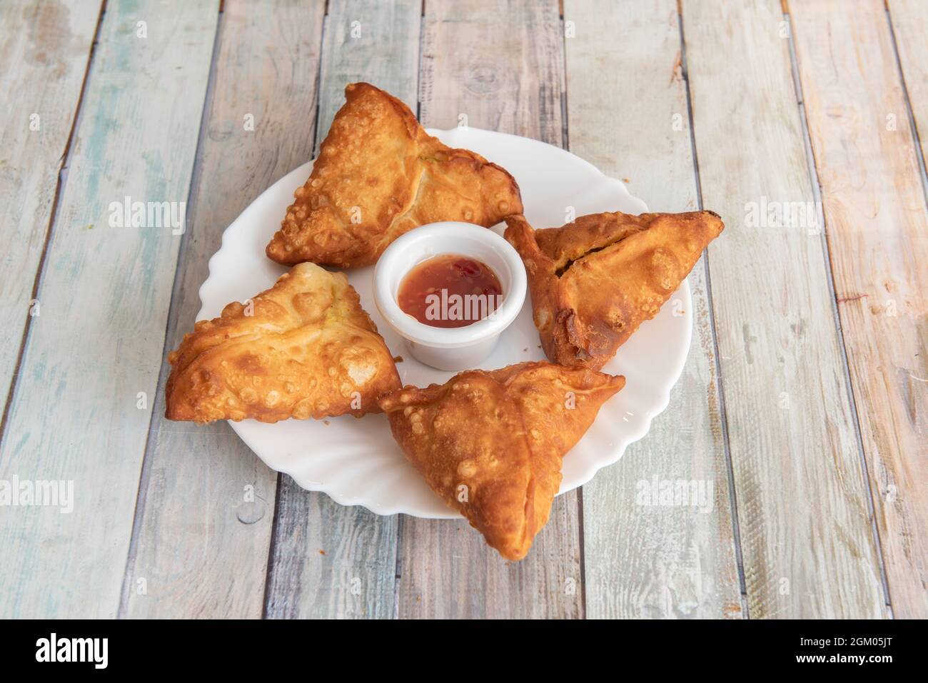 Vegetable samosas fried in oil with sauce in the center to dip Stock Photo