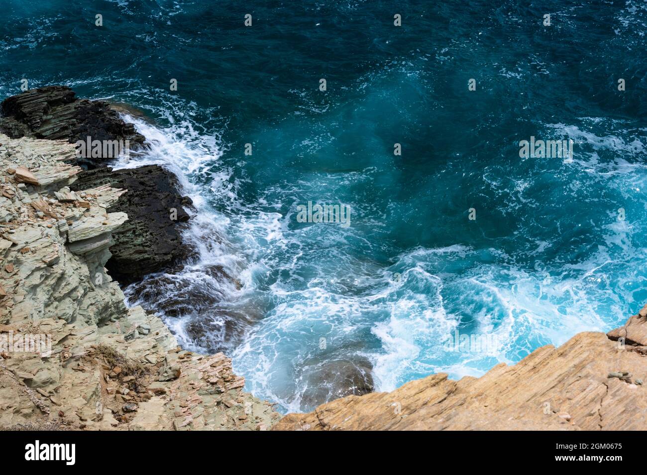 Aquamarine water with waves by a rocky coastline Stock Photo