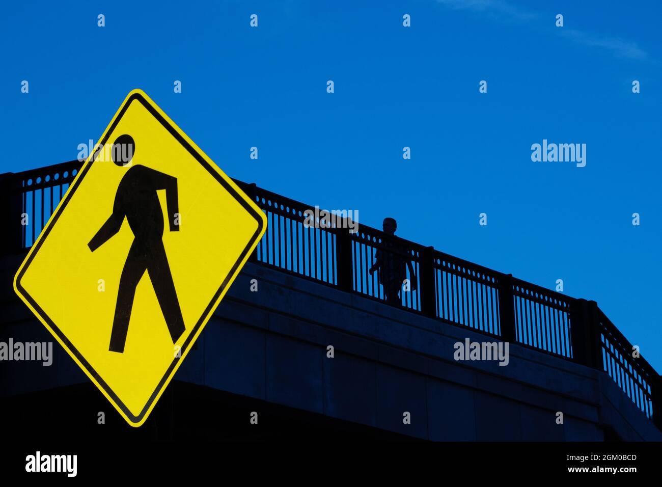 Silhouette of person walking on bridge with traffic walk sign Stock ...
