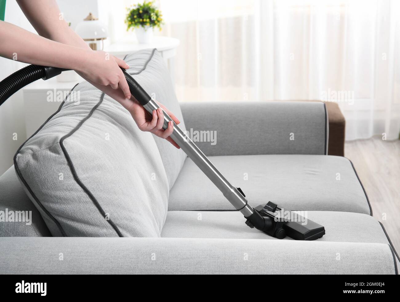 Woman cleaning couch with vacuum cleaner at home Stock Photo - Alamy
