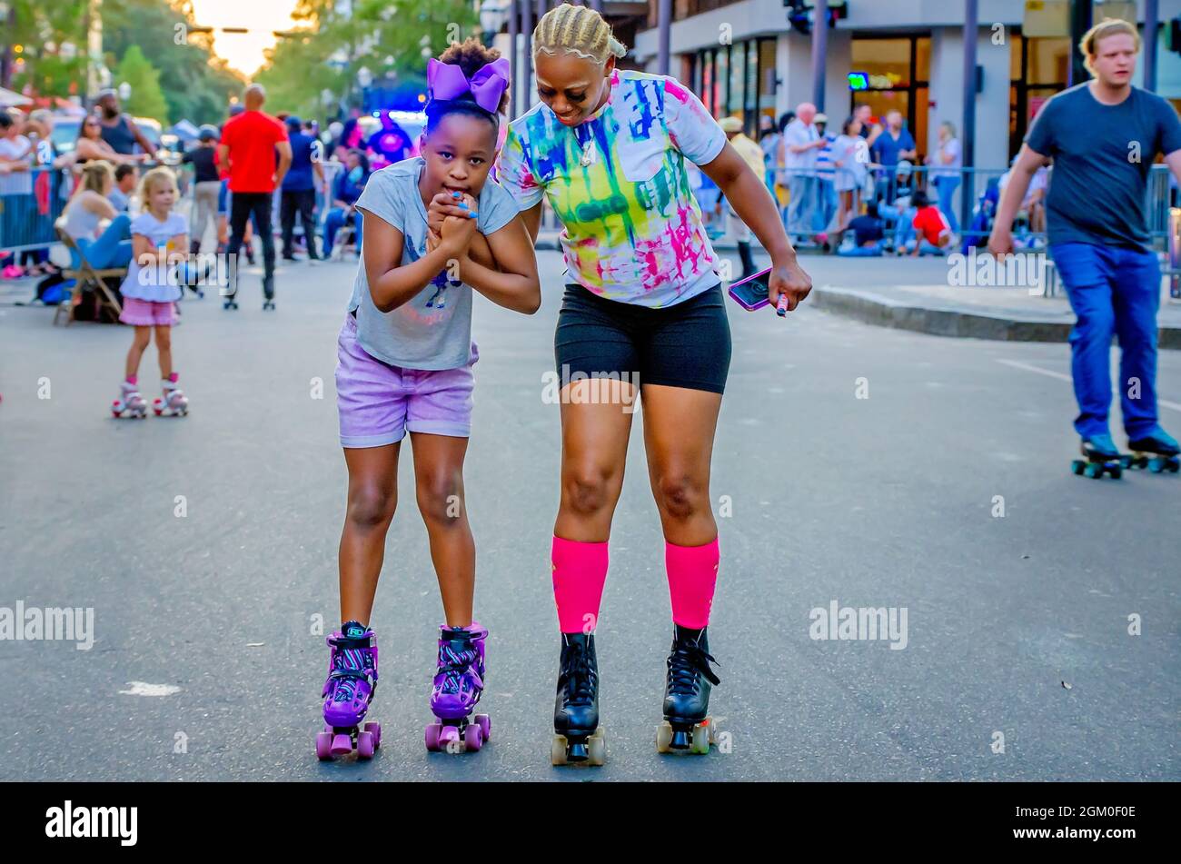 A woman teaches a young girl to rollerskate during Roll Mobile, Sept. 10, 2021, in Mobile, Alabama. The skate night is held monthly. Stock Photo