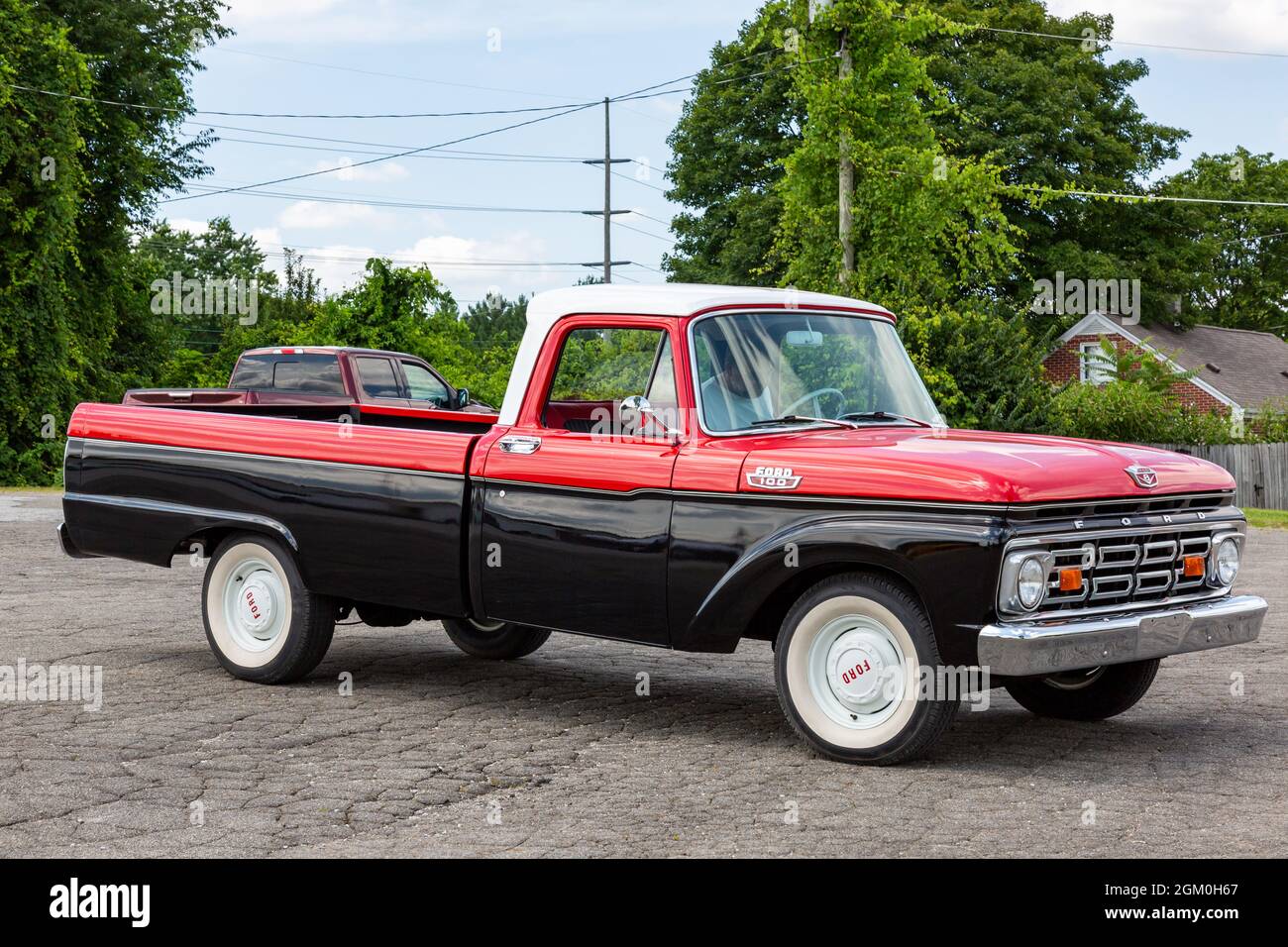 A classic black and red 1964 Ford F100 pickup truck on display at a
