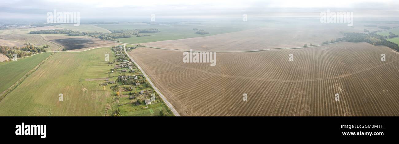 panoramic aerial view of countryside landscape with village among agricultural fields in the autumn morning mist Stock Photo