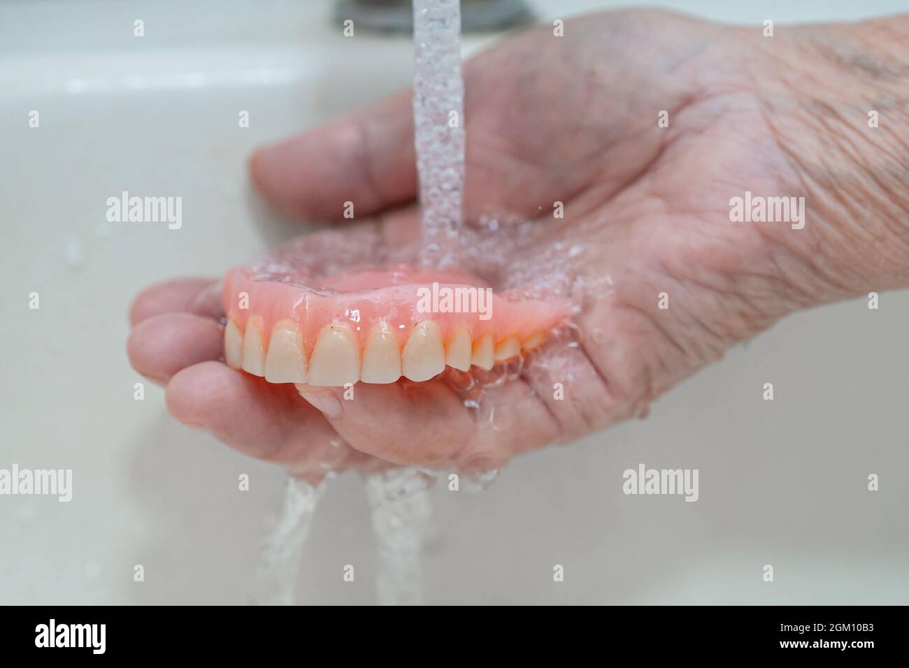 Asian senior or elderly old woman patient holding partial denture of