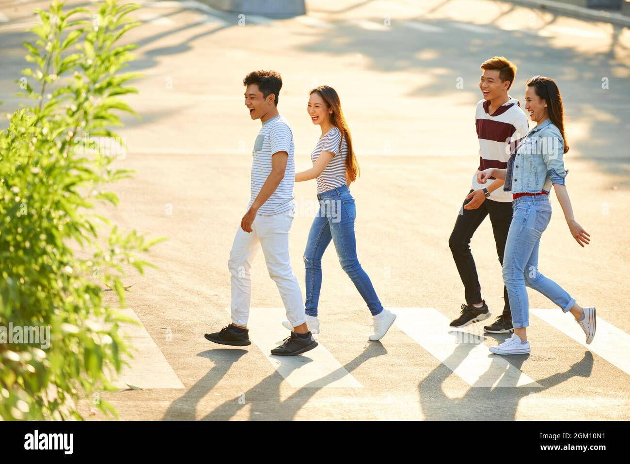 Cheerful excited young couples walking in city on sunny summer day and ...