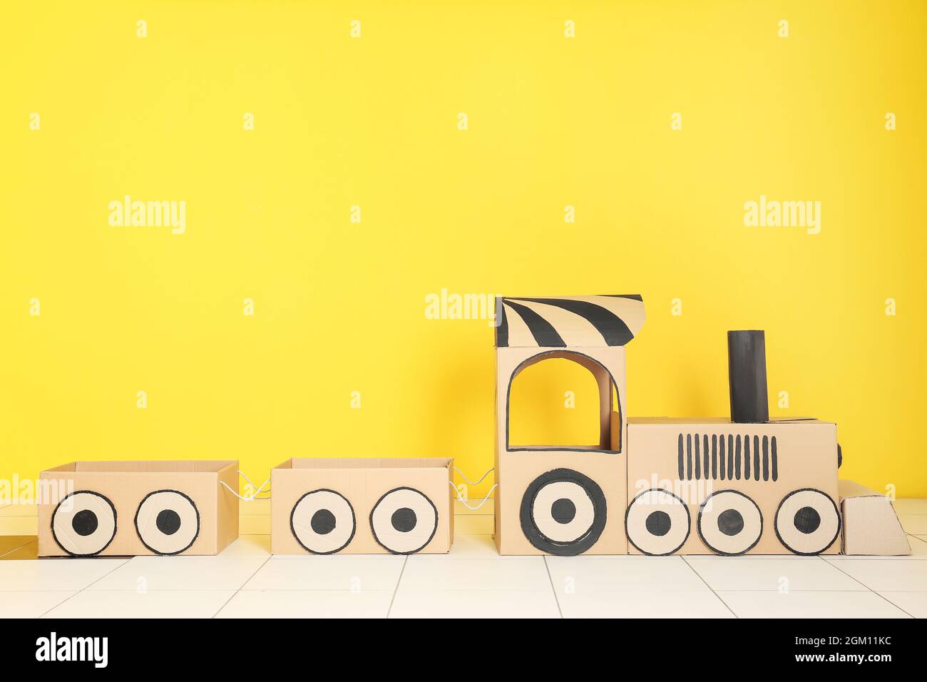 Cardboard train on color wall background Stock Photo - Alamy