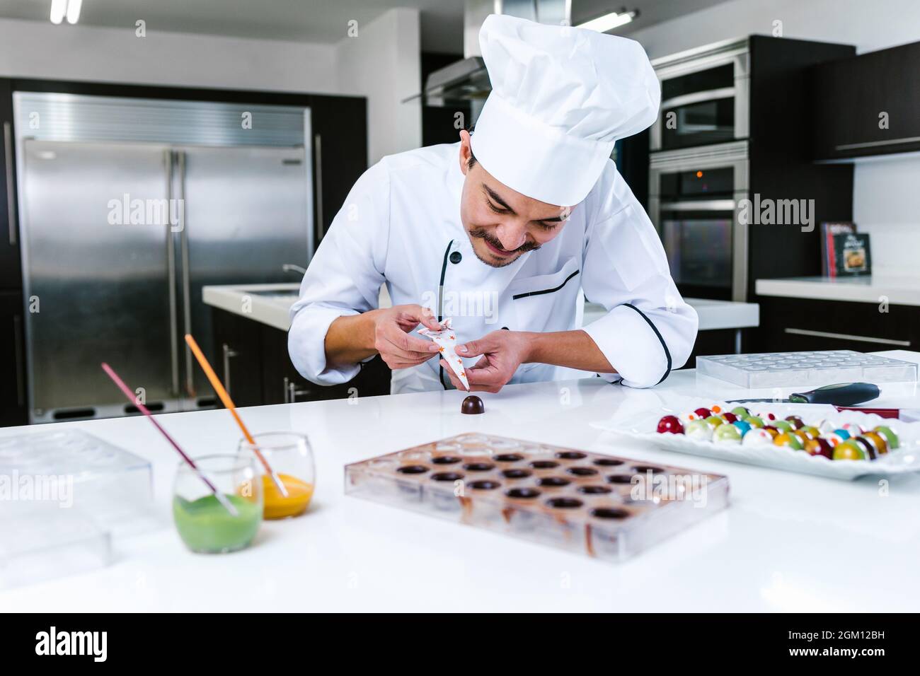 young latin man chocolatier in chef hat standing with mexican