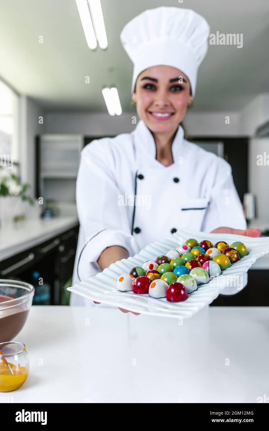 young latin woman chocolatier in chef hat with mexican chocolates