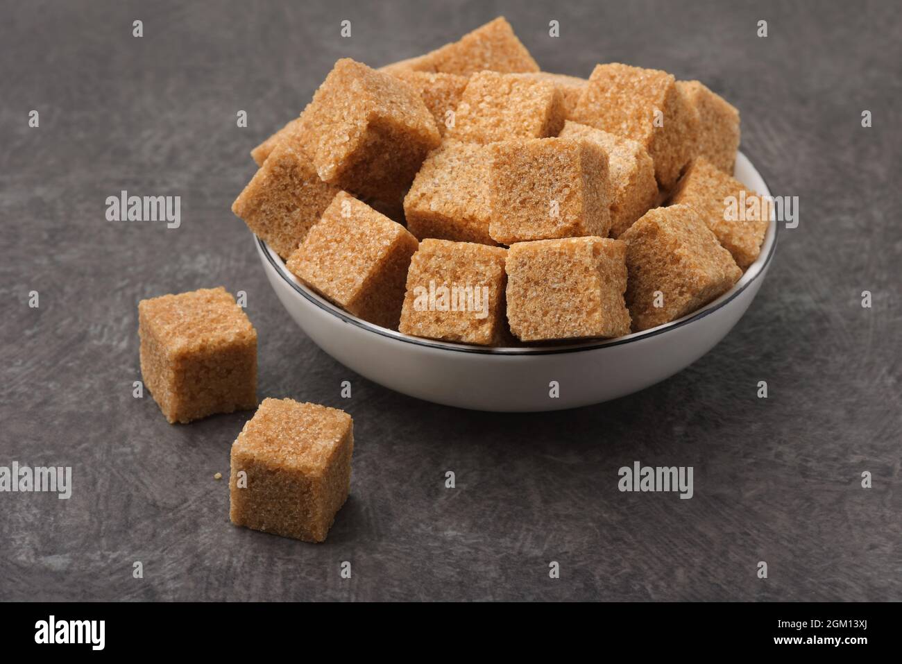 Brown unrefined cane sugar cubes on dark background Stock Photo